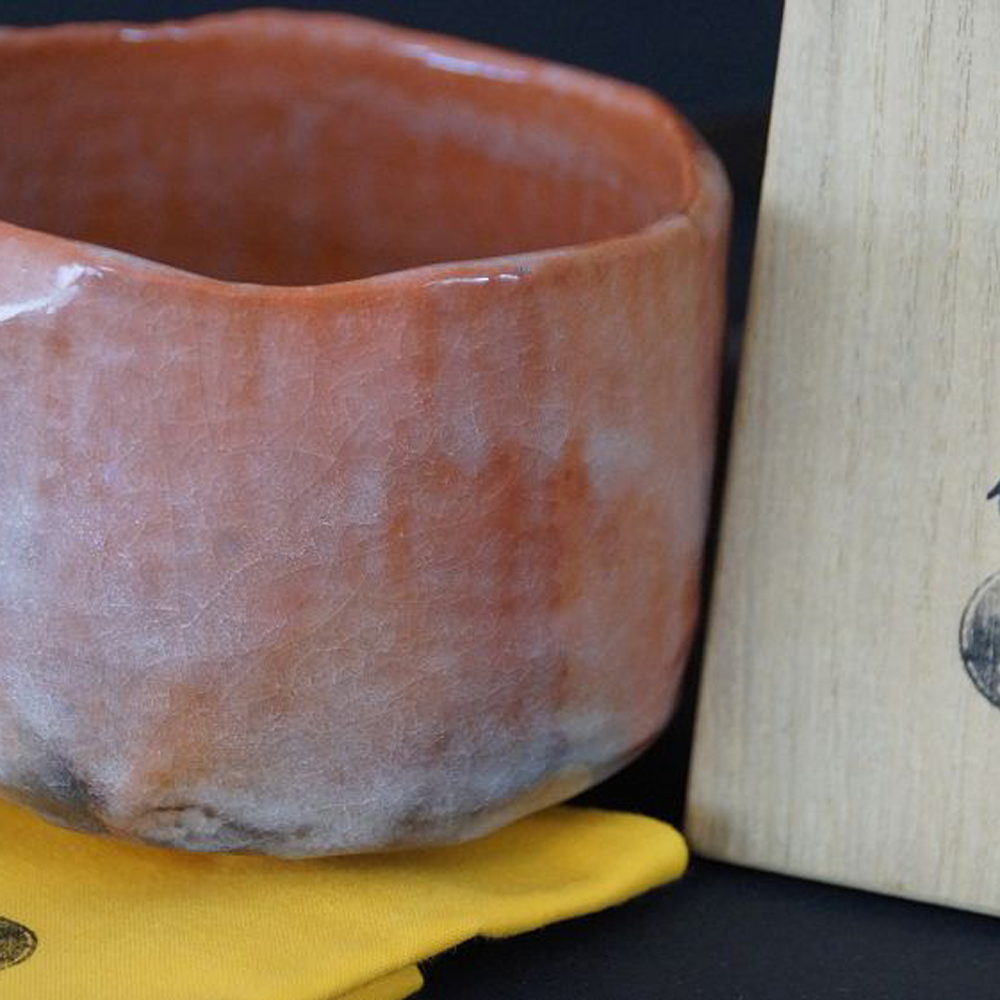 Nahaufnahme der Chawan Teeschale auf gelbem Tuch neben der Aufbewahrungsbox mit Kuenstlersiegel