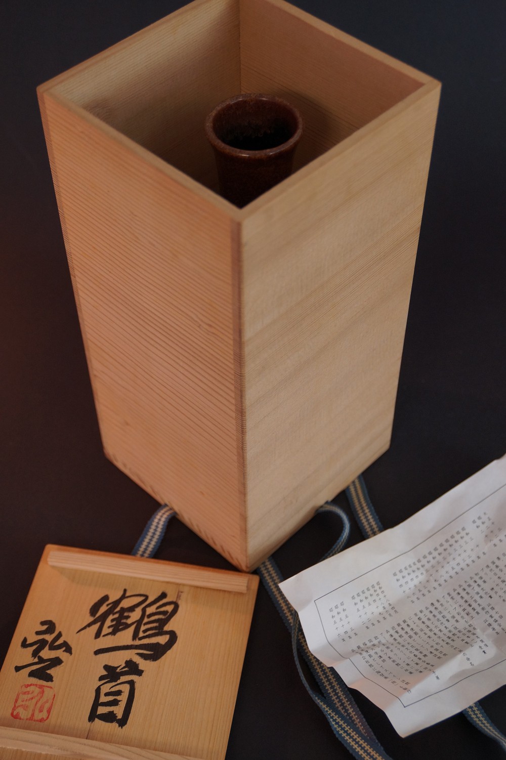 Die Vase stehend in der geoeffneten Aufbewahrungsbox neben Boxdeckel, Kordel und Echtheitszertifikat