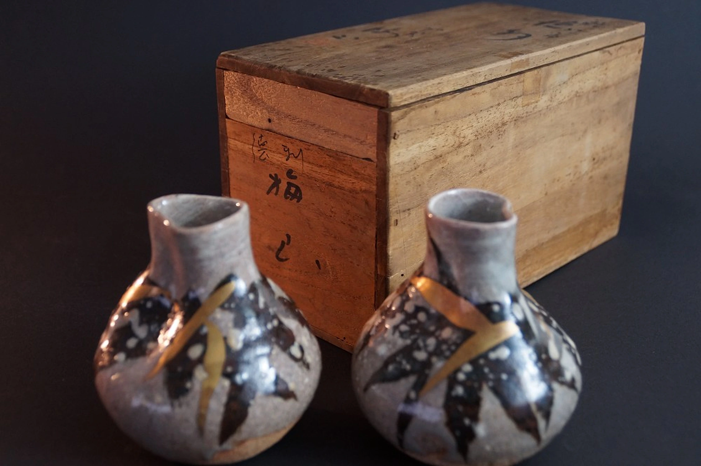 Le due bottiglie da sakè davanti alla scatola di conservazione firmata con calligrafia