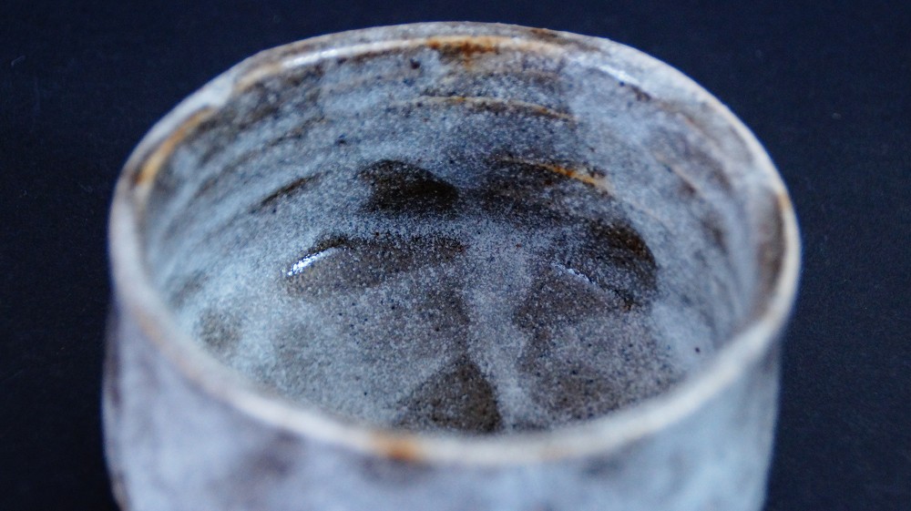 Blick von oben auf den Lippenrand und die Innenwand der Chawan aus Shino-Keramik von Kazufumi Wada mit dunklen Eisenflecken