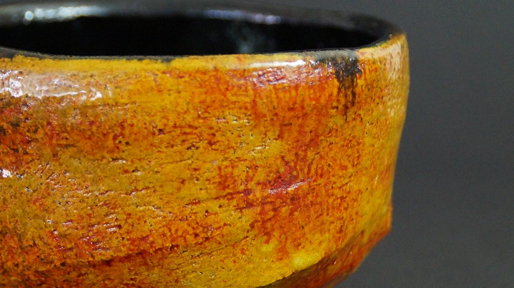 Gros plan de la glaçure extérieure ambrée sur le bord du chawan de Haryoku