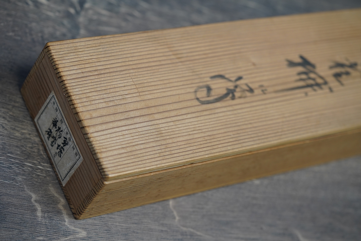 Deckel der hoelzernen Aufbewahrungsbox mit Kalligraphie-Beschriftung und Etikett