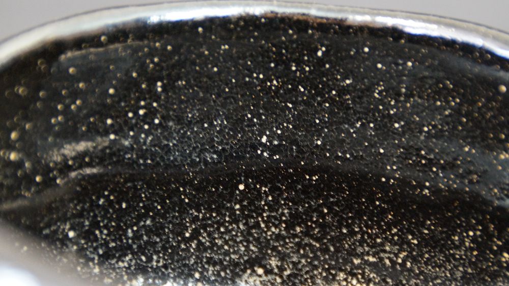 Gros plan sur le bord à la glaçure intérieure noire finement mouchetée du chawan en céramique Raku