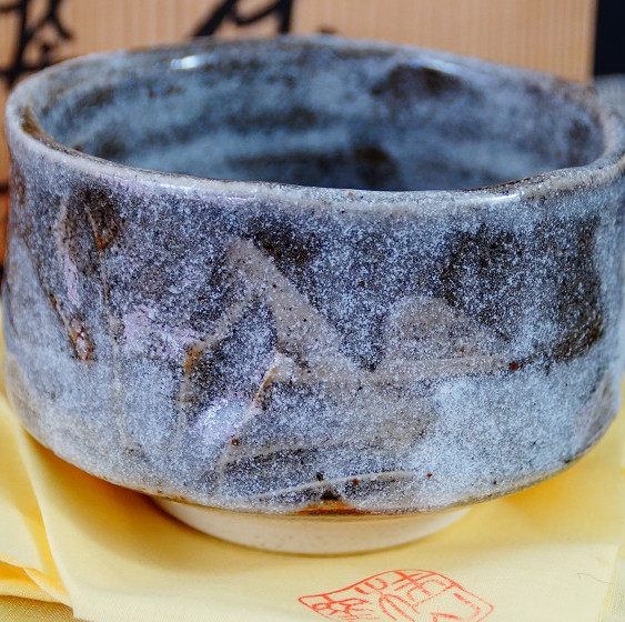 Chawan aus Shino-Keramik von Kazufumi Wada auf gelbem Tuch vor der Aufbewahrungsbox