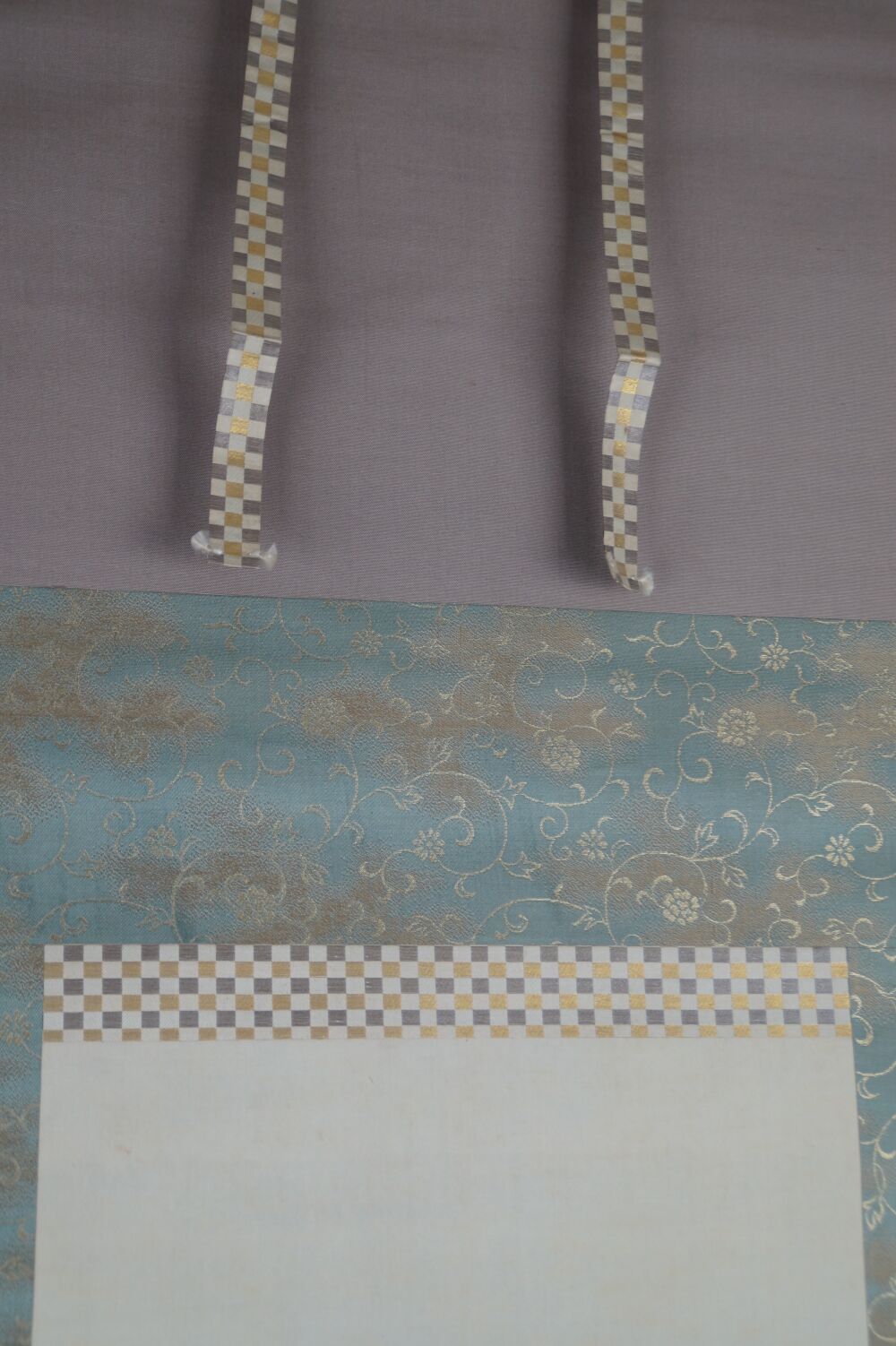 Detail view of the silk mounting with brocade pattern and hanging cords of the kakemono