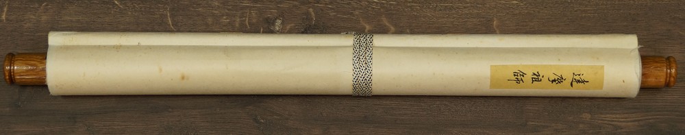 Zusammengerolltes Kakemono mit Titeletikett und Kordel sowie Jikusaki aus Holz