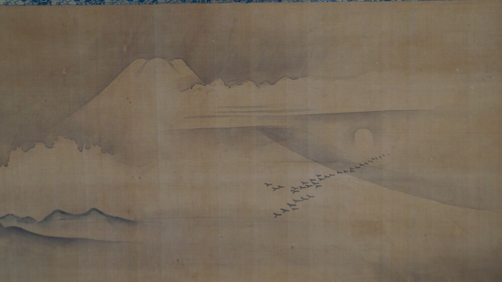 Nahaufnahme des Fuji-Gipfels mit ziehenden Gaensen vor der aufgehenden Sonne im Kakemono Fuji im Morgennebel