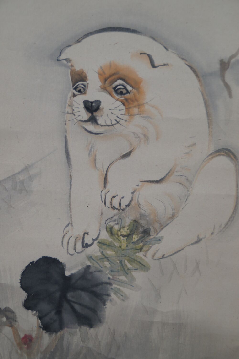 Close-up of the sitting puppy playing with a leaf in the kakemono Puppy in the Evening Glow Under Pines