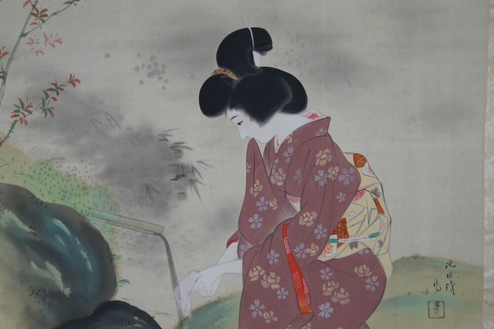 Ulteriore primo piano di mano e panno bianco presso lo scaricatore d'acqua in bambù nel kakemono dama in kimono presso lo stagno del giardino