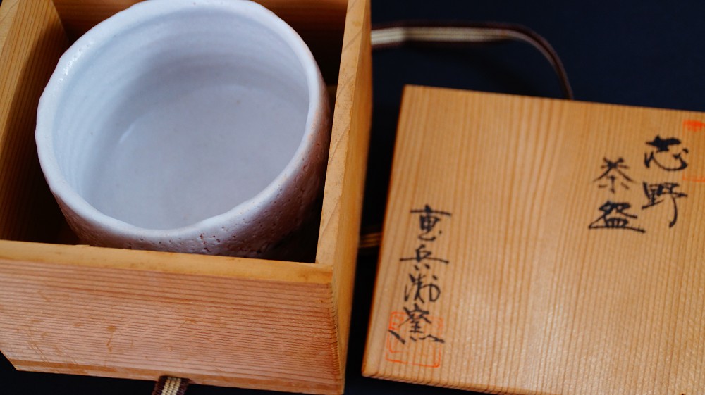 Chawan aus Shino-Keramik von Jyuzo Sato neben dem geoeffneten Deckel der Aufbewahrungsbox mit der Tuschebeschriftung Shino Chawan