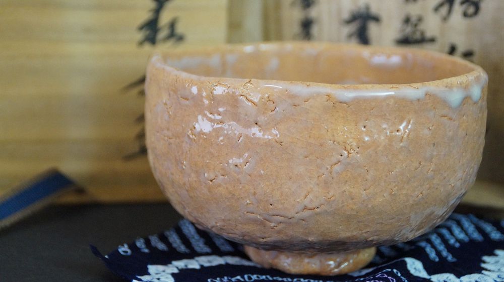 Chawan in ceramica di Hagi accanto alla scatola di conservazione firmata su tessuto a motivi blu