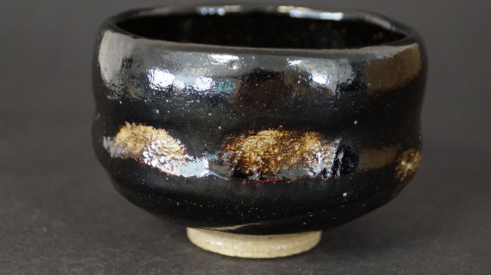 Weitere Ansicht der Chawan aus Raku-Keramik mit glaenzend schwarzer Glasur und goldfarbenen Akzenten