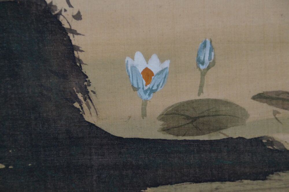 Close-up of the blue-and-white water lily blossom on the rock in the hanging scroll