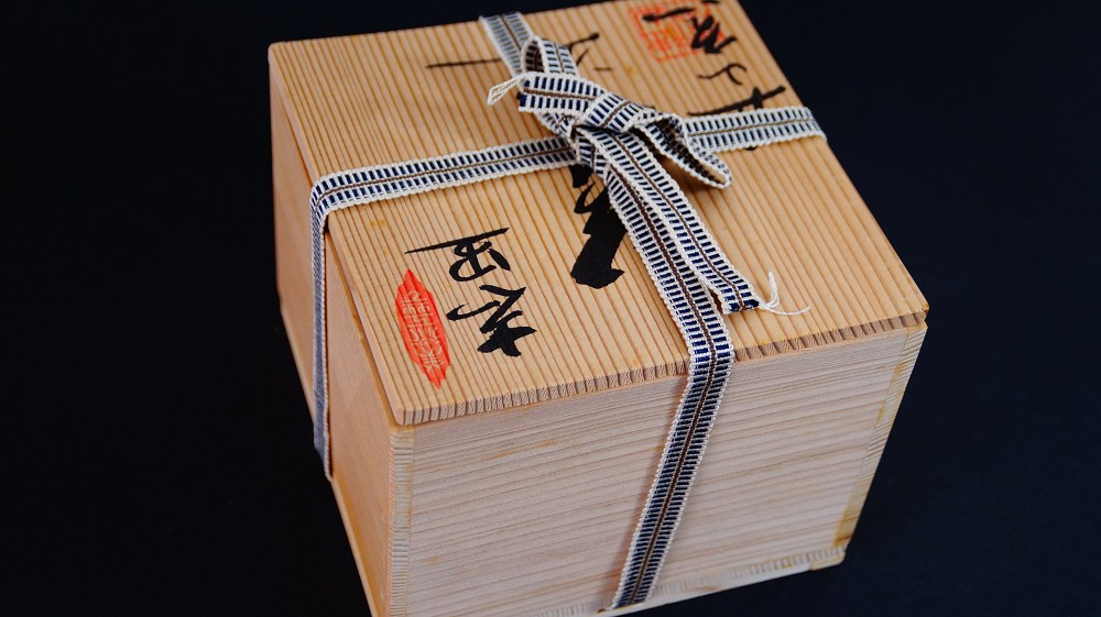 Geschlossene Aufbewahrungsbox der Chawan aus Shino-Keramik von Kazufumi Wada mit Tuschebeschriftung und rotem Kuenstlersiegel, verschnuert mit gemustertem Band