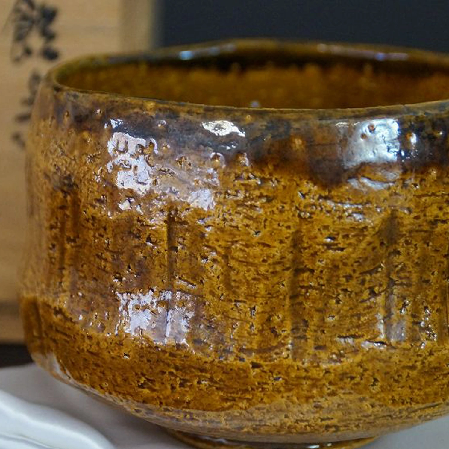 Chawan en céramique Raku par Rakunyu Yoshimura avec glaçure Ame couleur miel devant la boîte de rangement