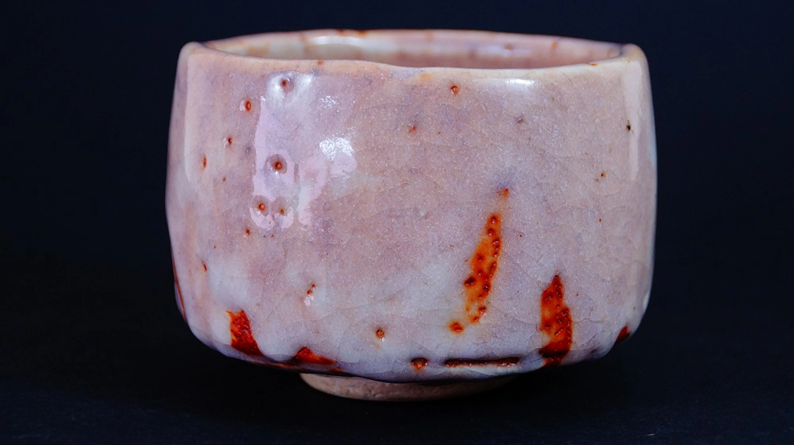 Chawan de cerámica Shino de Masayoshi Kato en vista frontal con esmalte color salmón y marcas de fuego rojas