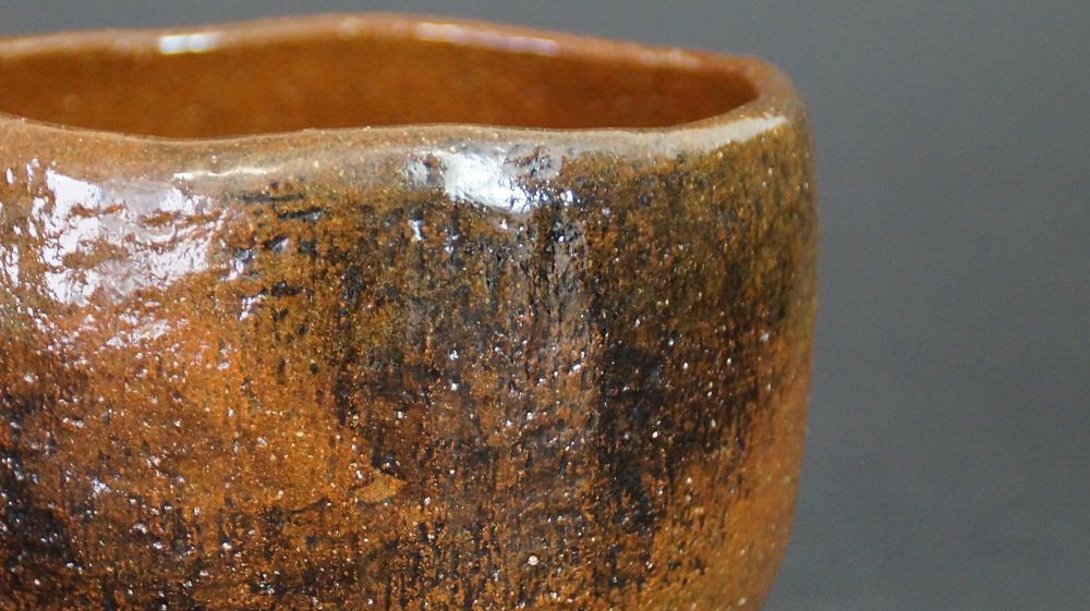 Primer plano del borde con vetas oscuras de esmalte del chawan de cerámica de Ohi