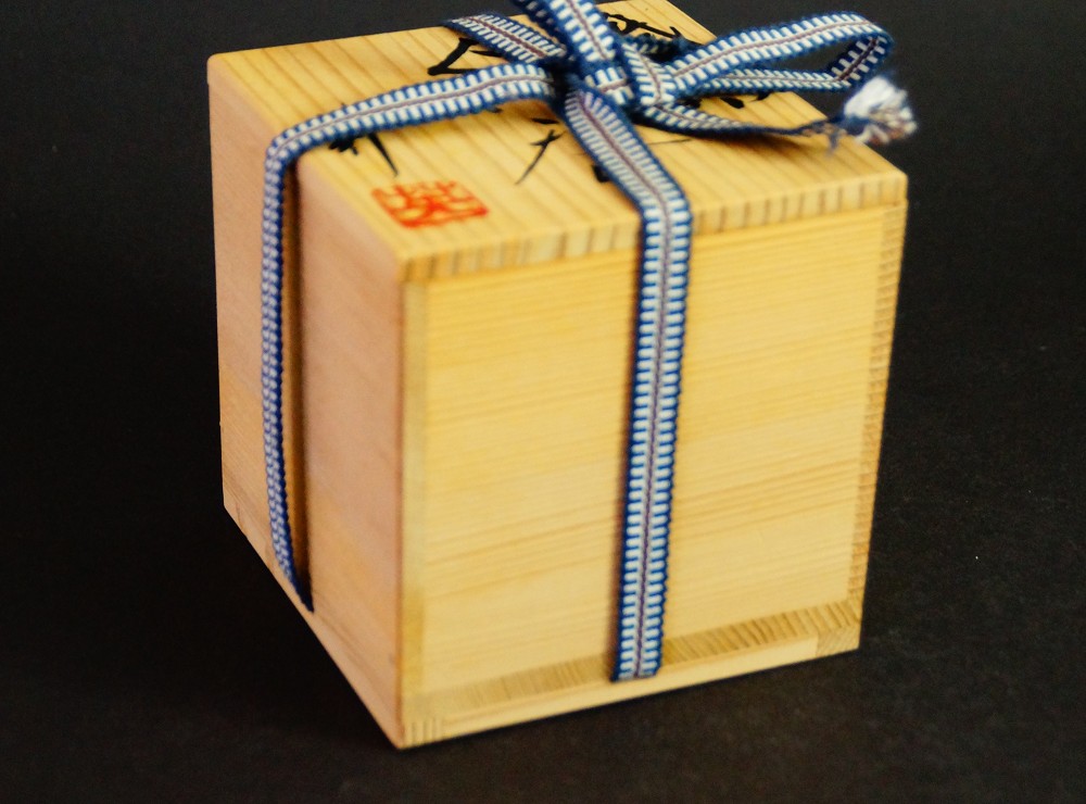 Verschlossene Aufbewahrungsbox aus Kiri-Holz mit blau-weisser Kordelverschnuerung und rotem Kuenstlersiegel