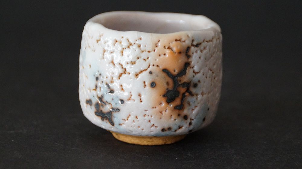 Frontalansicht des Guinomi aus Shino-Keramik von Takeshi Kato mit craquelierter Glasur und Eisenflecken
