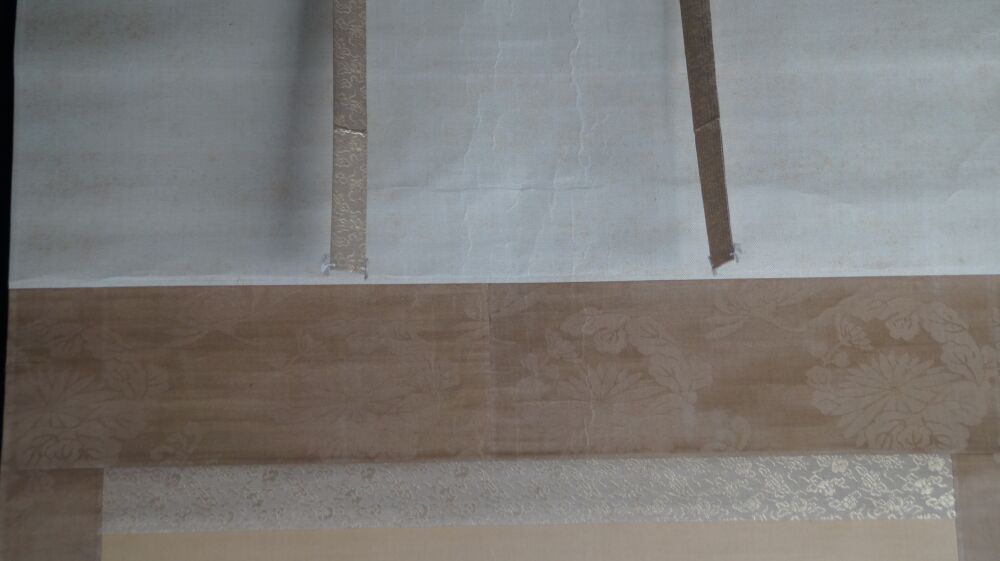 Detail view of the cream-colored silk mounting with blossom pattern and hanging cords of the Kakemono Rising Sun