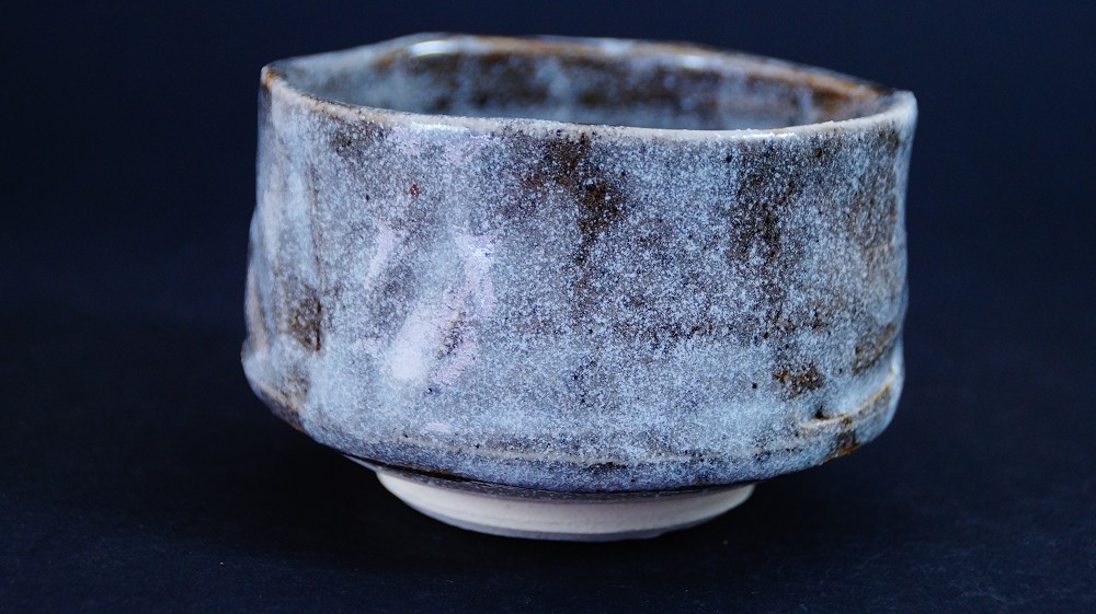 Weitere Seitenansicht der Chawan aus Shino-Keramik von Kazufumi Wada mit graublauer Nezumi-Shino-Glasur und dunklen Eisenflecken