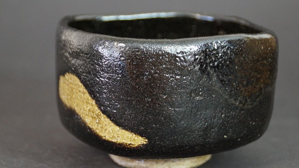 Weitere Ansicht der Chawan aus Raku-Keramik mit diagonalem goldfarbenem Glasurstreifen