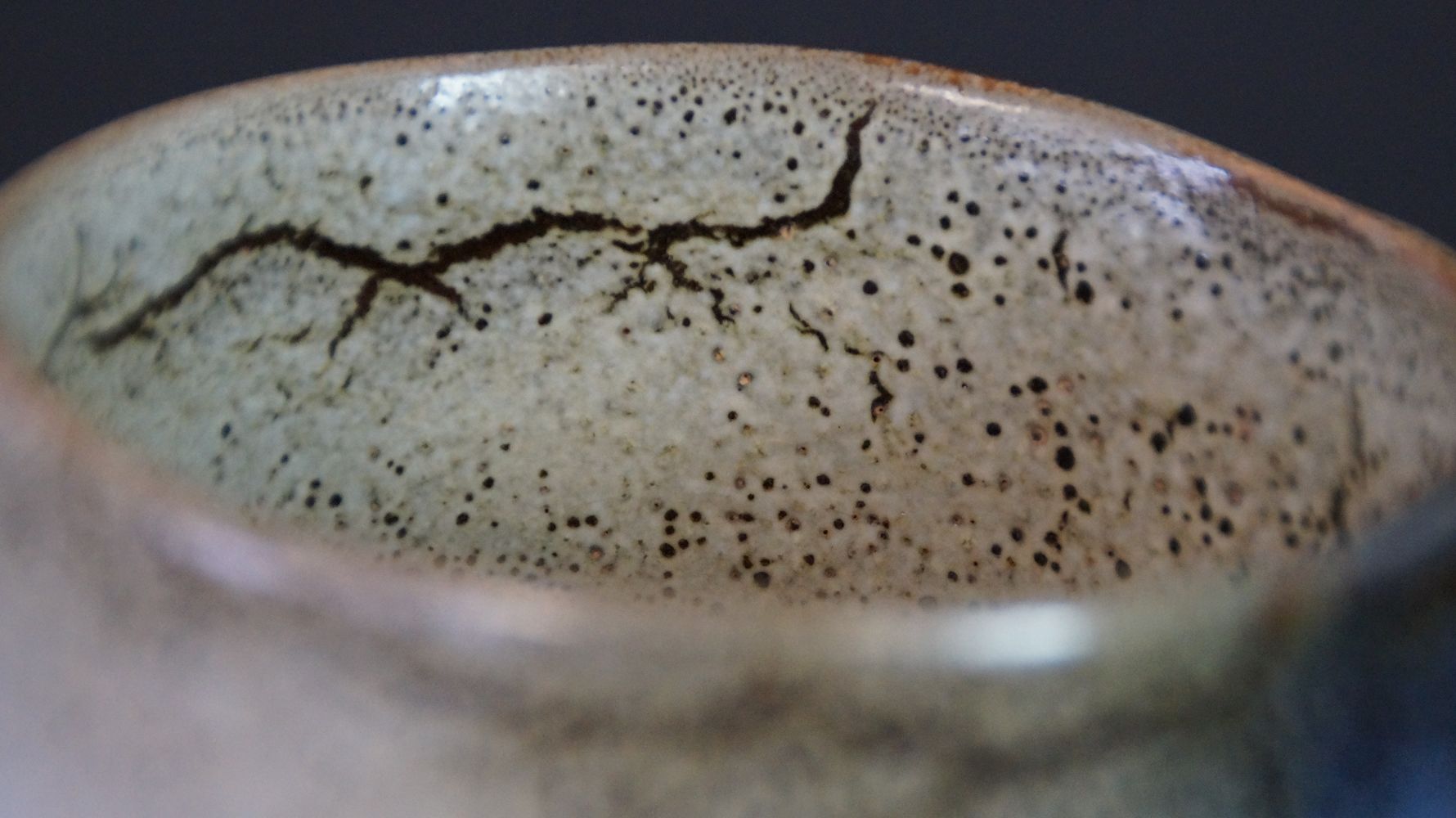 Nahaufnahme des Randes mit craquelierter, dunkel gesprenkelter Glasur der Chawan Teeschale aus Kyoto-Keramik