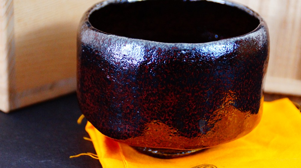 Chawan aus Raku-Keramik von Shoraku Sasaki neben der Aufbewahrungsbox auf orangefarbenem Tuch