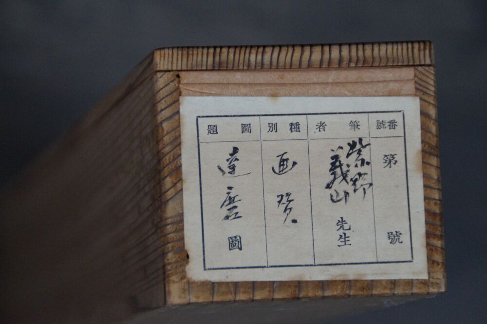 Vista detallada de la inscripción caligráfica con el nombre del artista y el título de la obra en la caja de conservación del kakemono Bodhidharma directo al corazón