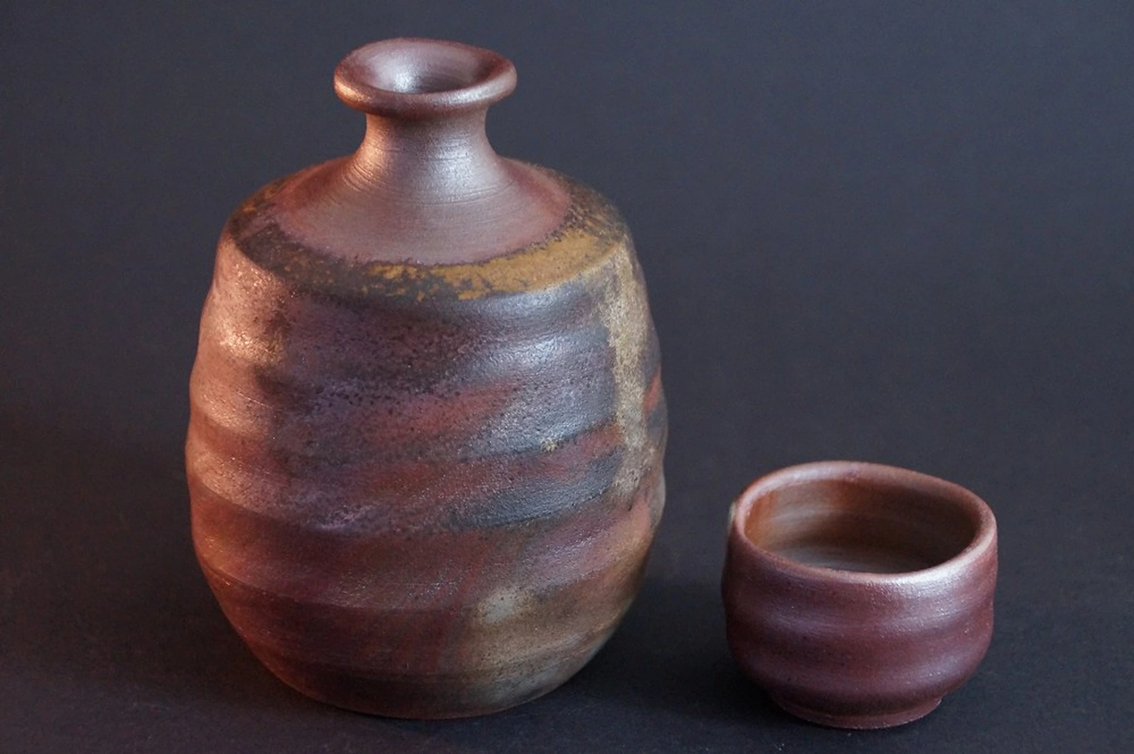 Vue de face du flacon à saké en céramique de Bizen tourné à la main, à côté un guinomi (non inclus)