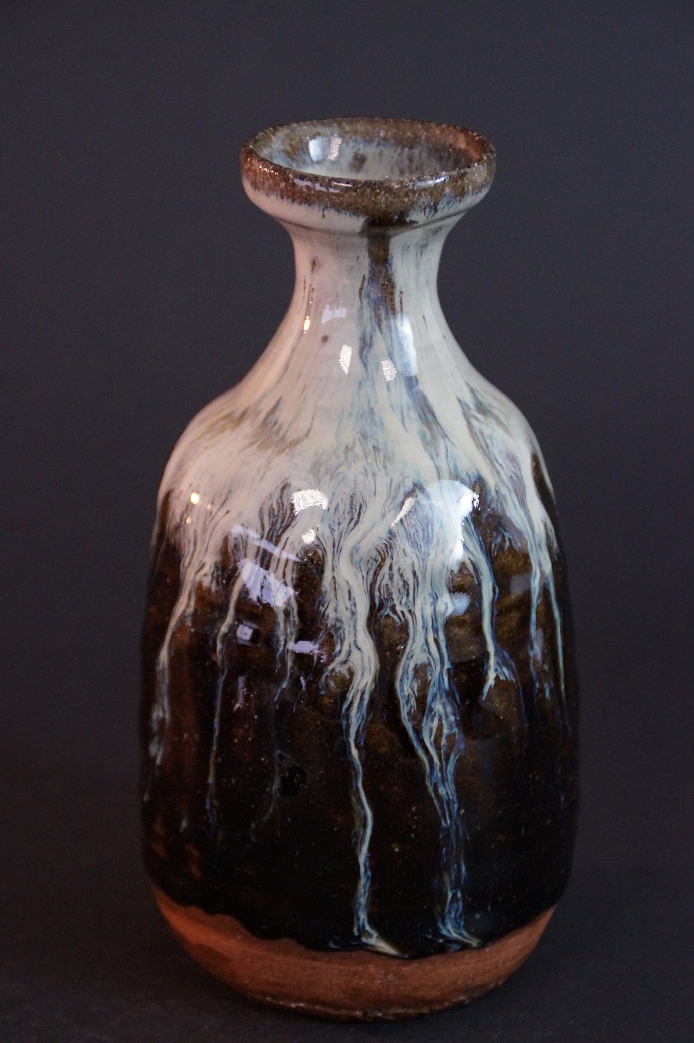 Frontalansicht der handgetoepferten Karatsu Sake Flasche mit fliessender Glasur