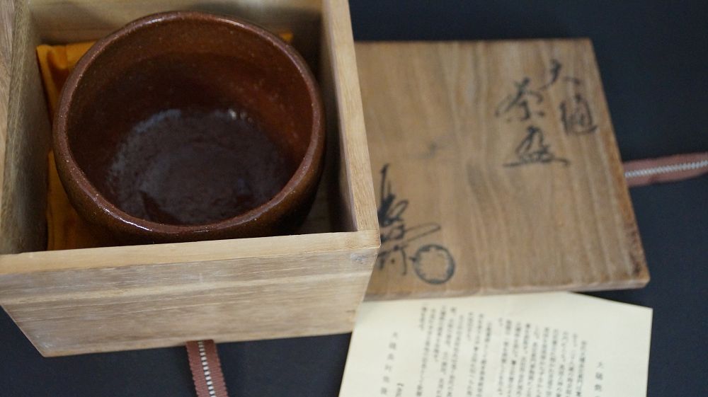 Chawan de cerámica de Ohi en la caja de conservación abierta junto a la tapa firmada de la caja y el certificado de autenticidad