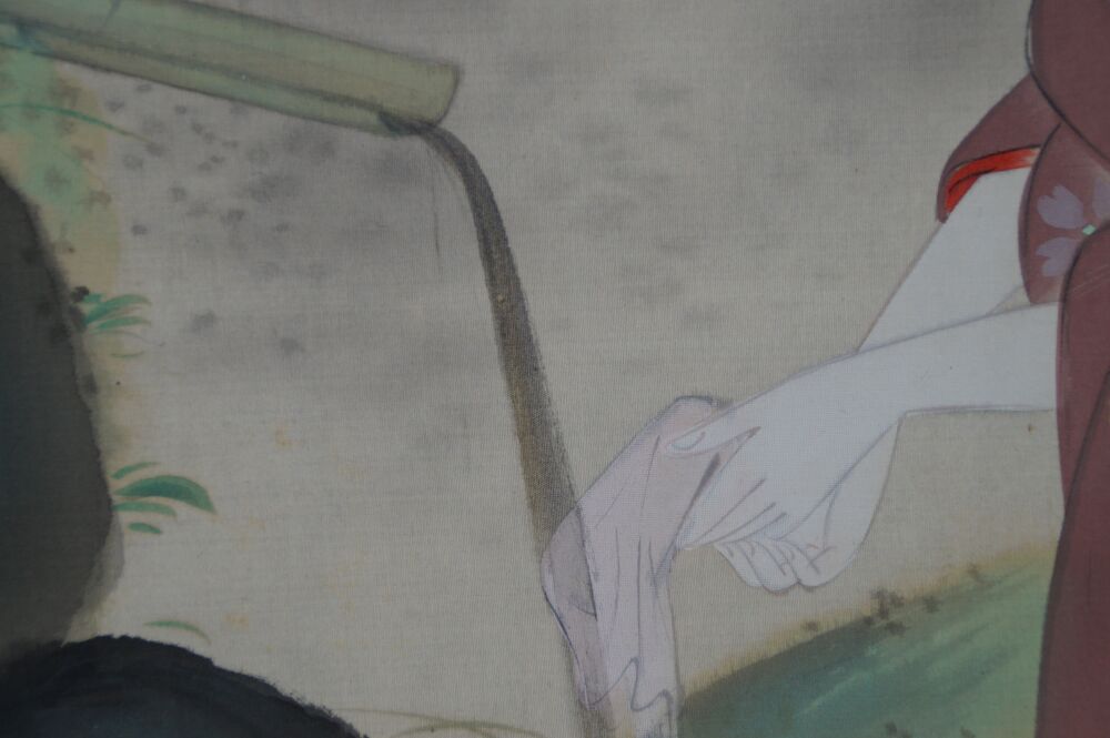 Ulteriore veduta ravvicinata della mano e del panno presso lo sputatore d'acqua in bambù con roccia coperta di muschio nel kakemono dama in kimono presso lo stagno del giardino
