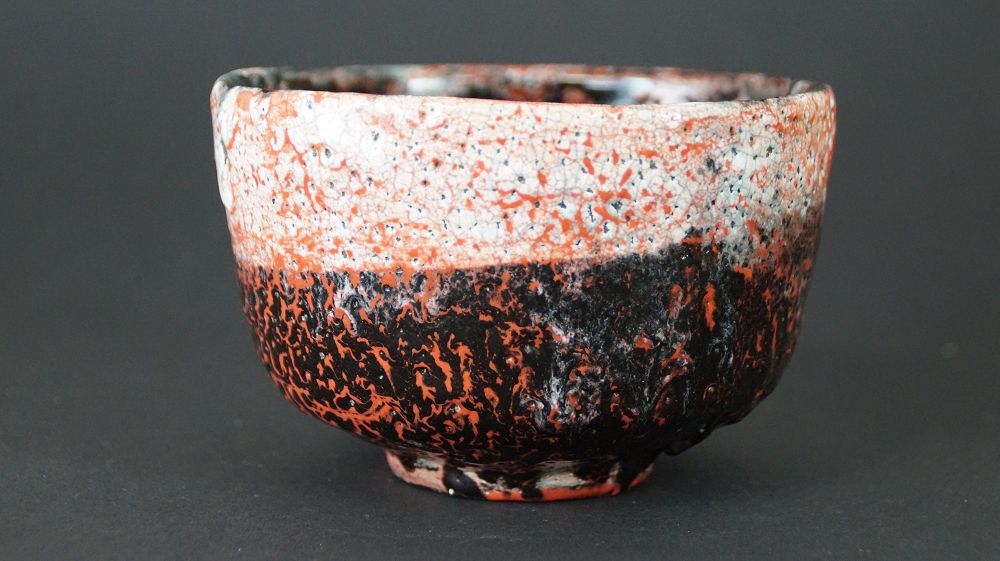 Chawan Teeschale aus Raku-Keramik von Ryohei Kusakabe in der Gesamtansicht mit rot-schwarzer Glasur