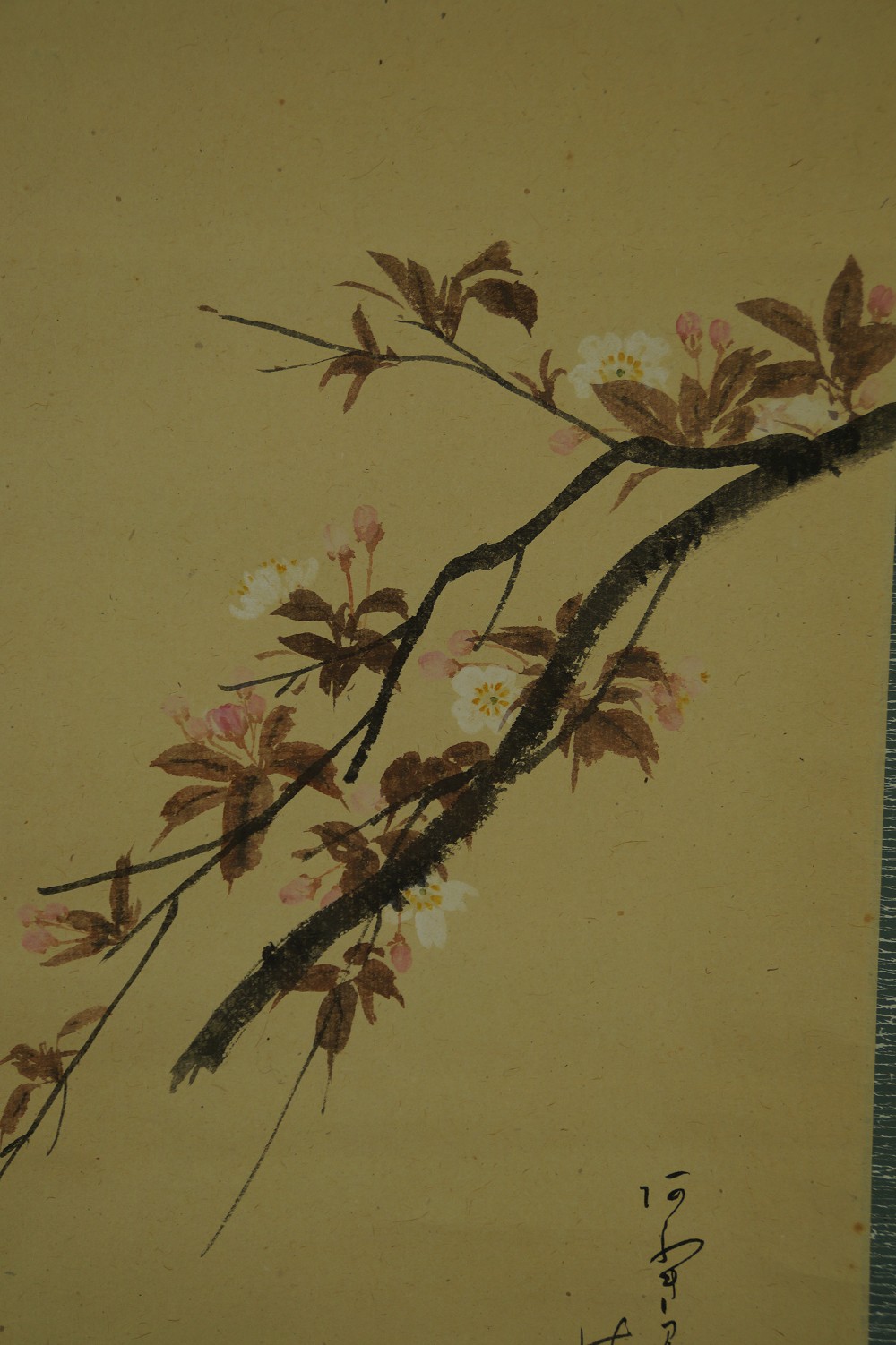 Primer plano de la rama con flores de cerezo y partes de la inscripción poética