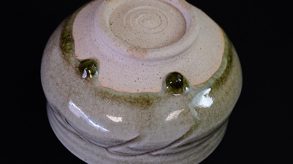 Nahaufnahme des Chawan-Bodens mit spiralfoermigen Drehspuren und gruenen Glasurtropfen