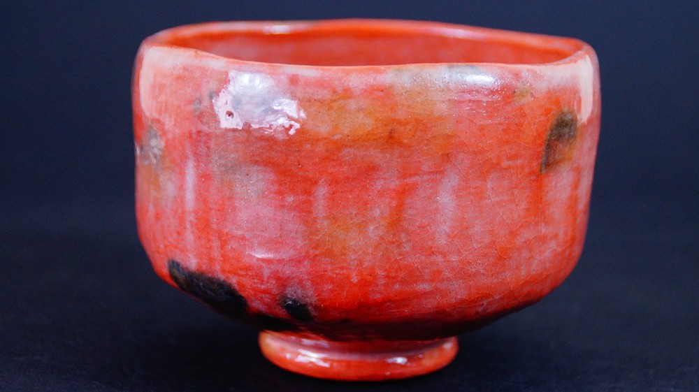 Weitere Seitenansicht der Chawan aus Raku-Keramik von Waraku Kawasaki mit changierender roter und oranger Glasur