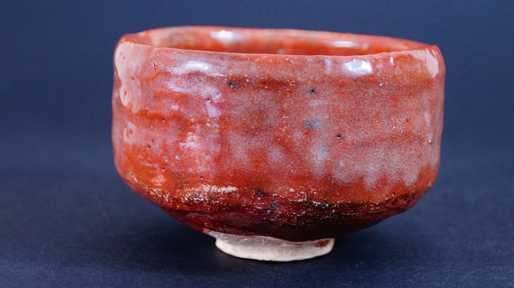 Otra vista lateral del chawan de cerámica Raku de Sairi Hotoku con manchas oscuras en el esmalte
