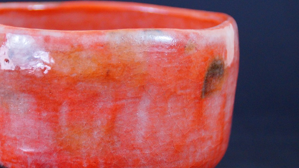 Nahaufnahme des Lippenrandes der Chawan aus Raku-Keramik von Waraku Kawasaki mit rissiger roter Glasur