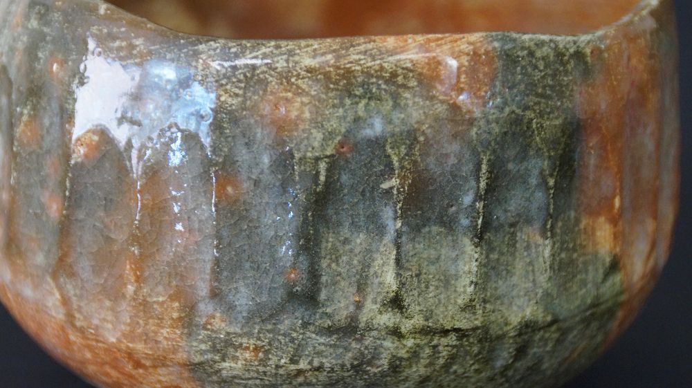 Extreme Nahaufnahme der fliessenden Glasurstruktur der Chawan Teeschale aus Raku-Keramik
