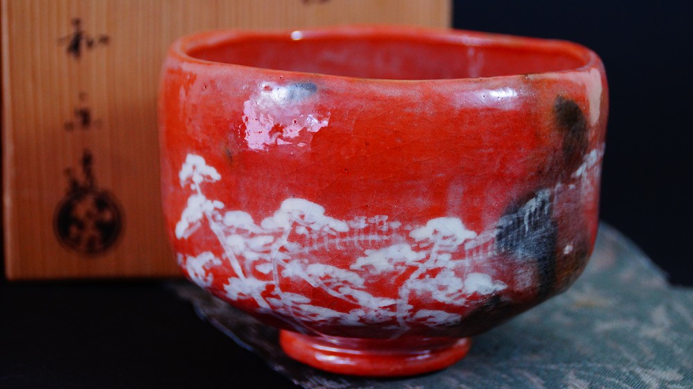 Chawan aus Raku-Keramik von Waraku Kawasaki neben der Aufbewahrungsbox auf strukturiertem Tuch