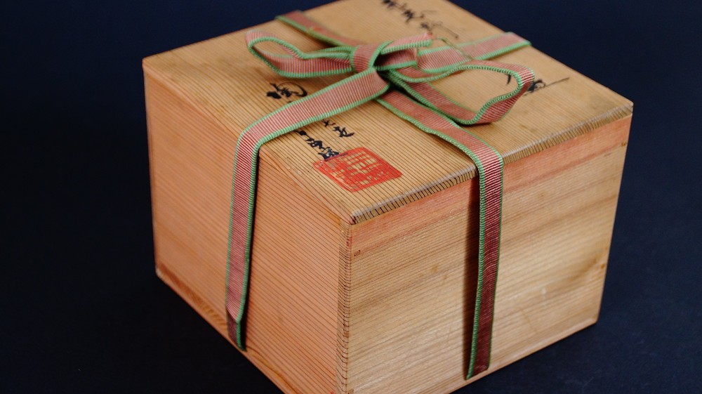 Geschlossene Aufbewahrungsbox der Chawan aus Shino-Keramik von Masayoshi Kato mit rot-gruener Verschnuerung und rotem Kuenstlersiegel