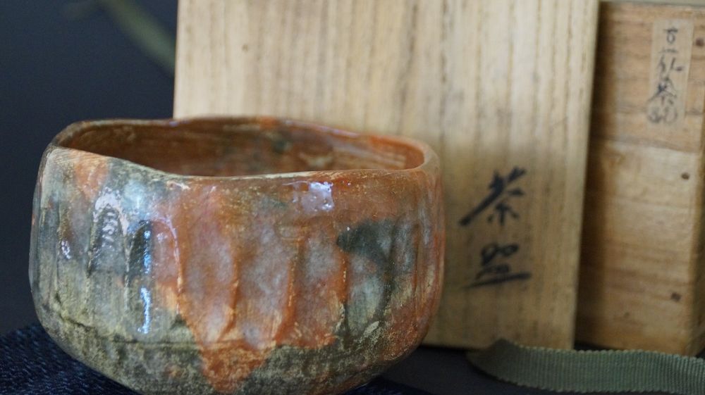 Nahaufnahme der Chawan Teeschale vor der beschrifteten Aufbewahrungsbox mit der Aufschrift Chawan