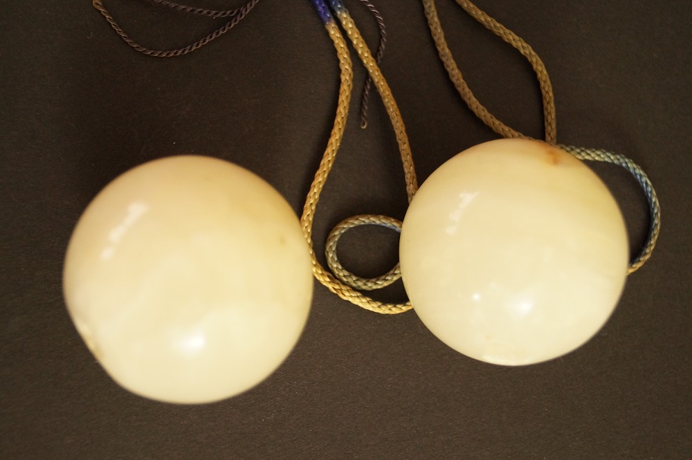Due sfere di pietra naturale chiare con cordoncini affiancate primo piano pietra 3