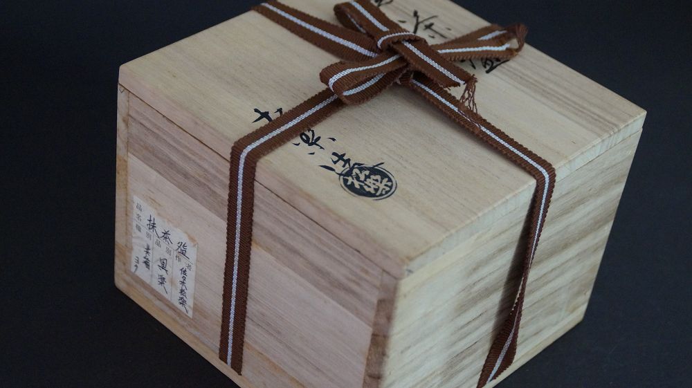 Caja de conservación cerrada, atada con cinta marrón, del cuenco de té de cerámica Raku con etiqueta