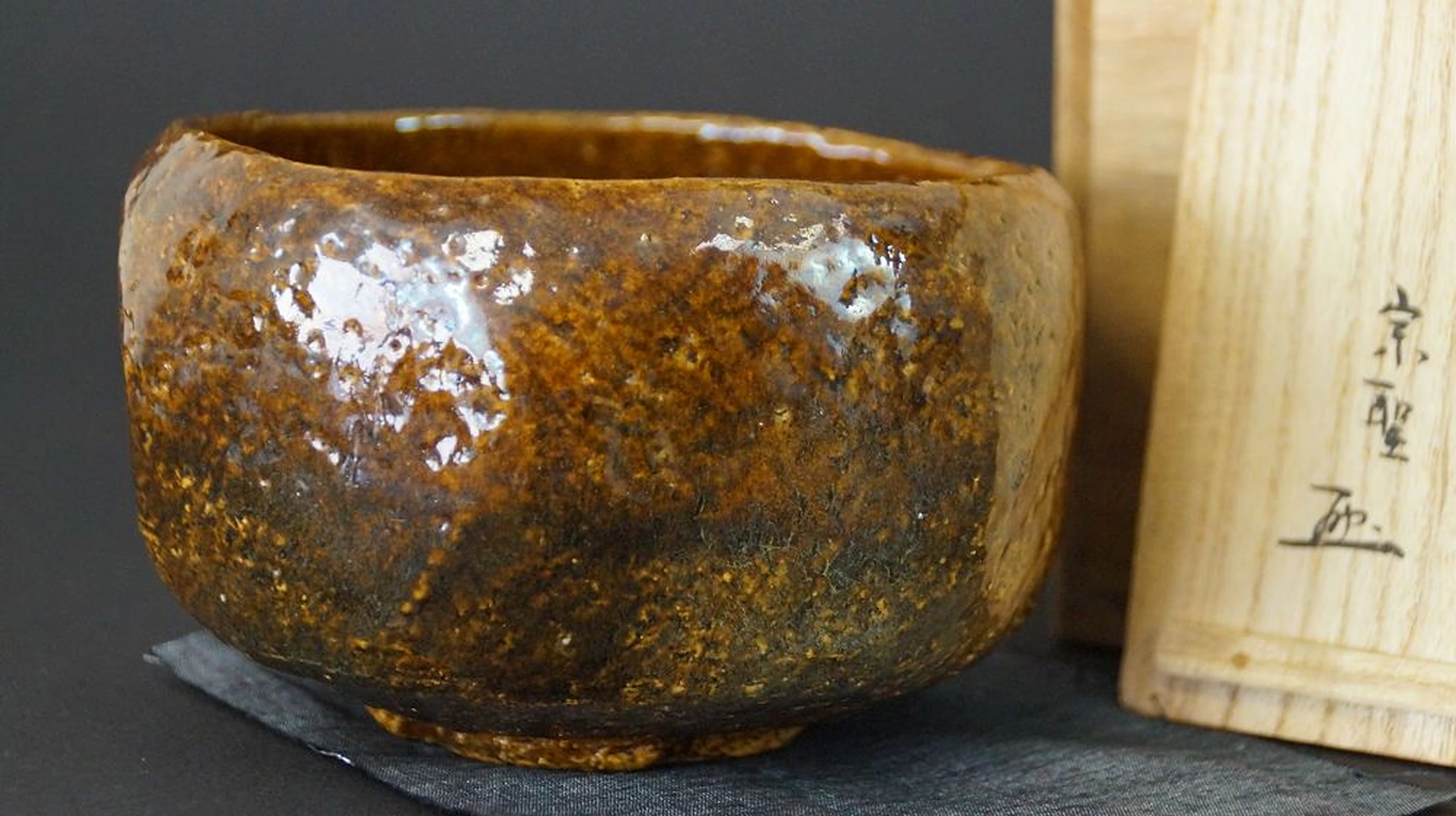 Cuenco de té chawan de cerámica Ōhi junto a la caja de conservación firmada