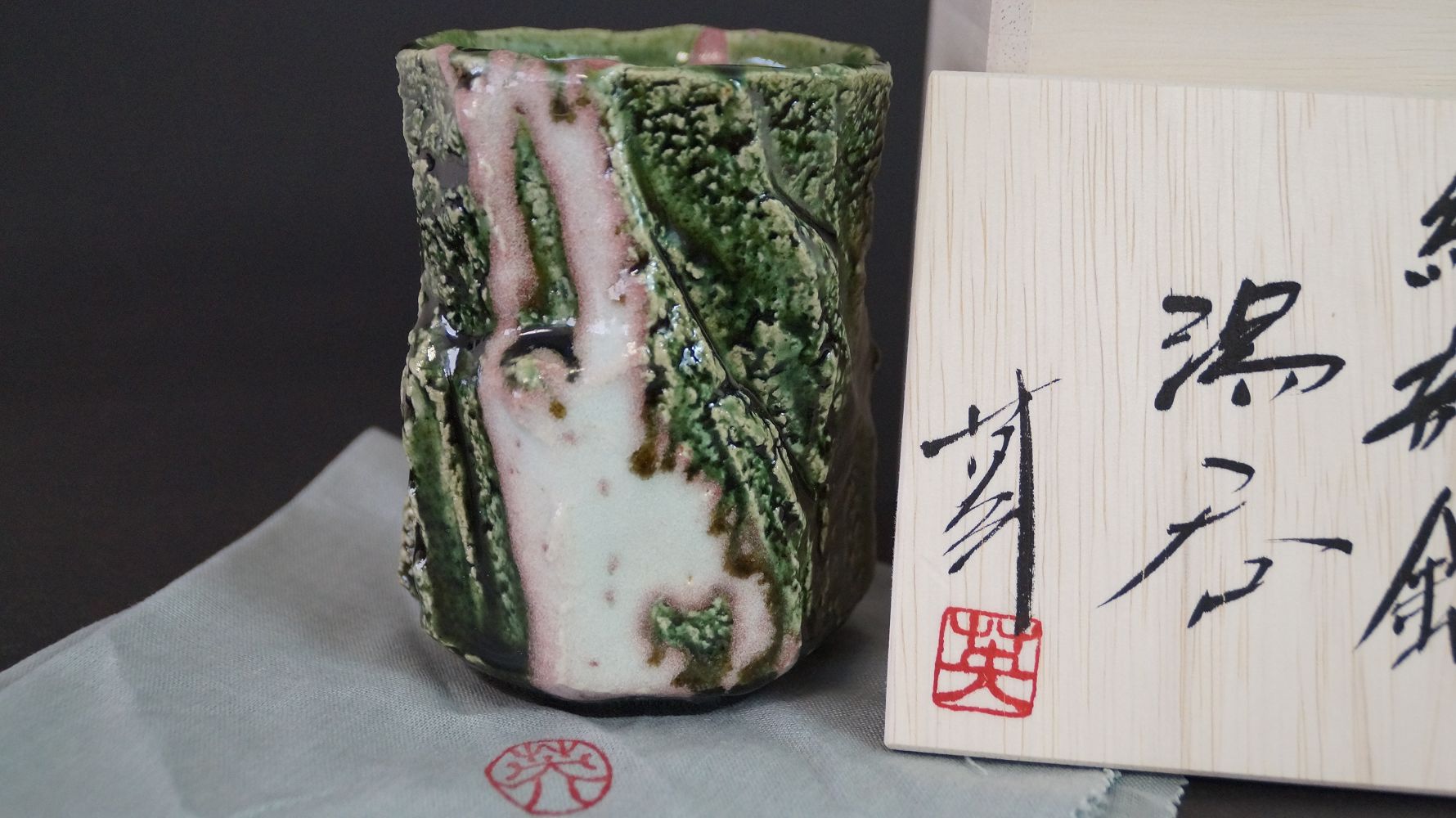 Yunomi Tee-Schale aus Oribe-Keramik neben der signierten Aufbewahrungsbox mit rotem Kuenstlersiegel