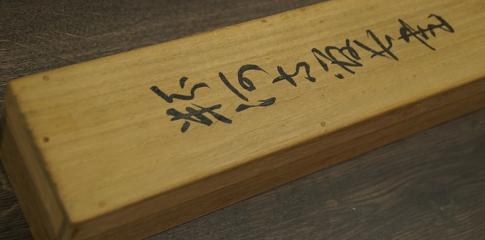 Nahaufnahme der hoelzernen Aufbewahrungsbox mit Tuscheinschrift