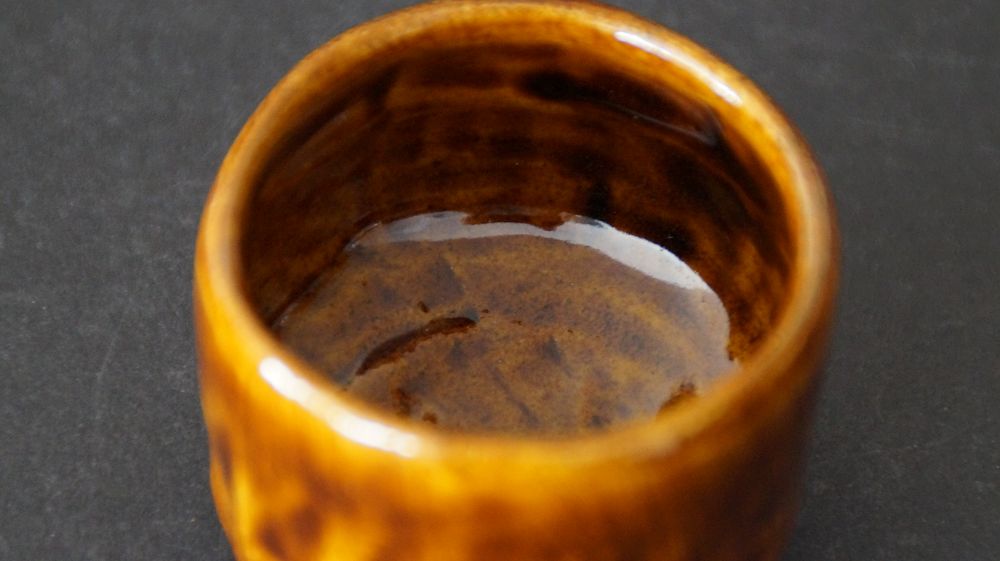 Innenansicht des Guinomi aus Ohi-Keramik von Ohi Cho mit glaenzender bernsteinfarbener Glasur