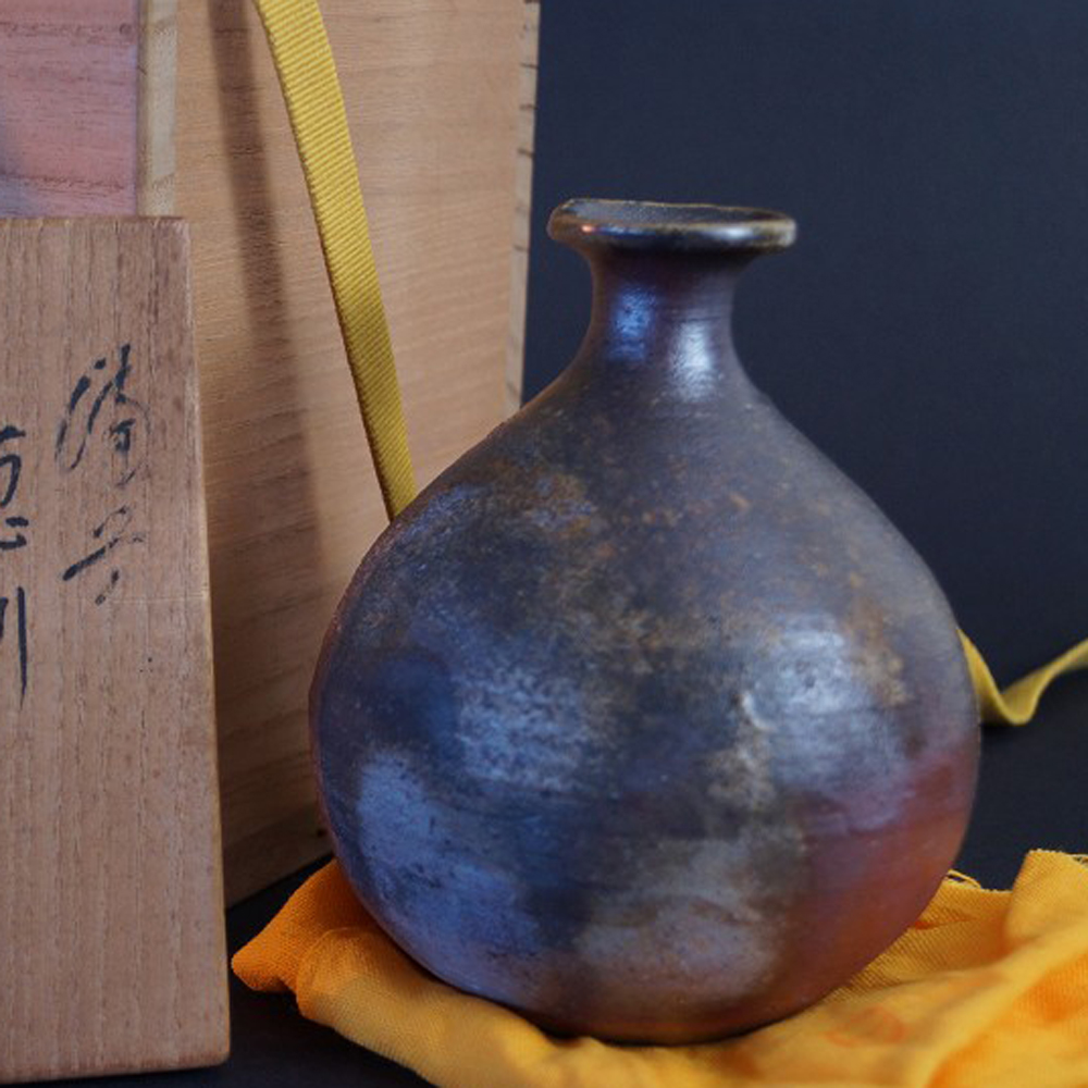 Vorschau-Nahaufnahme der Bizen Sake Flasche auf gelbem Tuch mit Aufbewahrungsbox